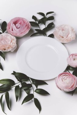 Pembe güller ve beyaz arka planda çiçekler olan güzel bir masa.