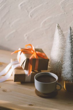 Noel hediyeleri ve tahta arka planda bir fincan kahve olan hediye kutusu..