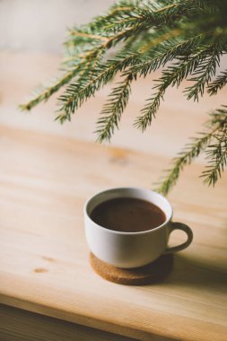 Bir fincan kahve ve ahşap zemin üzerinde köknar ağacı.