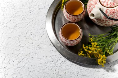 Çiçekli çay seremonisi ve beyaz arkaplanda çaydanlık