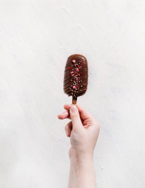 Hafif bir arka planda çikolatalı dondurma tutan el. 