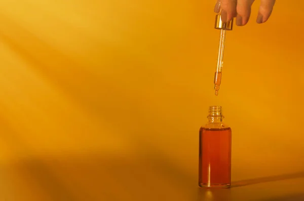 bottle of oil with a dropper on a yellow background