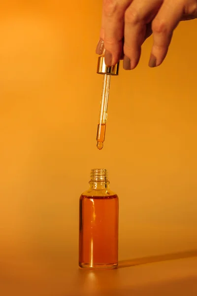 Mano Sosteniendo Una Botella Aceite Frasco Vidrio Sobre Fondo Amarillo — Foto de Stock