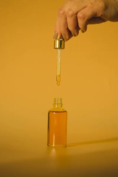 Mano Con Botella Aceite Frasco Vidrio Sobre Fondo Amarillo — Foto de Stock