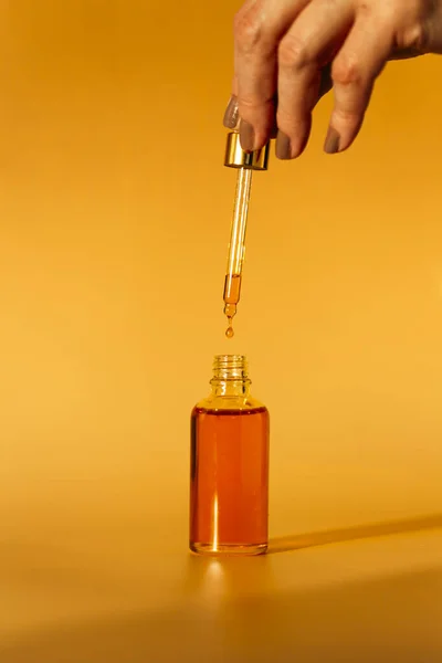 Dłoń Kobiety Trzymającej Butelkę Oleju Szklanym Słoiku Żółtym Tle — Zdjęcie stockowe