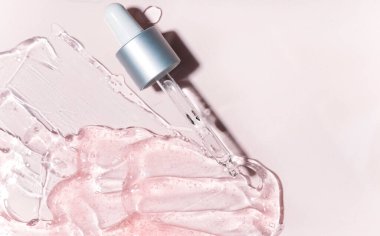 Pembe arka planda damlatıcısı olan şeffaf jöle serumunun yakın görüntüsü