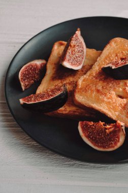 Siyah bir tabakta servis edilen incirli ekmek tostu.