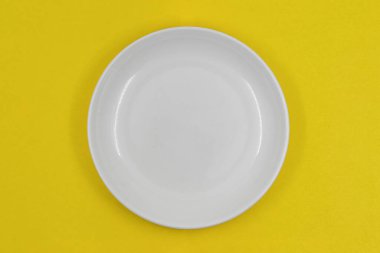 Tablo ayarı, sarı arkaplanda boş beyaz plaka, fotoğraf tam yukarıda.