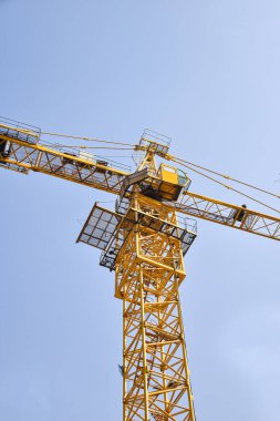 İnşaat alanında mavi gökyüzüne karşı kule vinci.