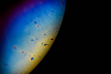 Evrendeki soyut çok renkli psikedelik gezegen. Karanlık arka plandaki yabancı bir gezegen gibi yakın plan sabun köpüğü.