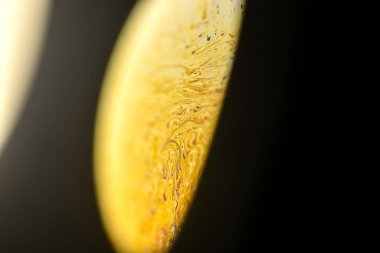 Yakın plan sabun köpüğü, evrendeki sarı bir gezegen tarafından tamamen aydınlatılmış karanlık arka plan üzerinde döndürmek gibi.