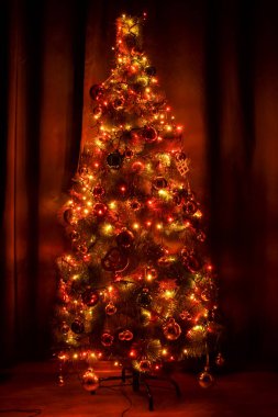 Karanlıkta süslenmiş Noel ağacı. Parlak sarı ve kırmızı ışıklar.