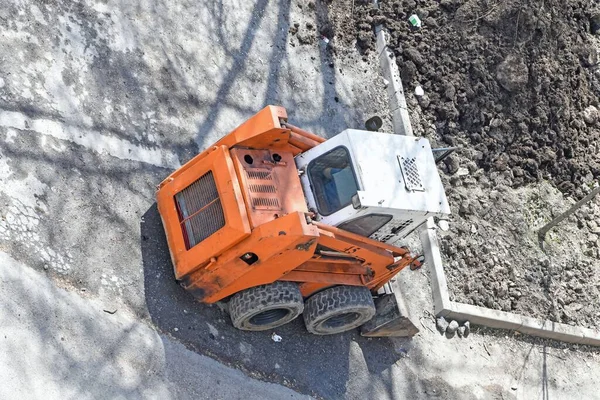 Tekerlekli mini yükleyici şehir peyzajı üzerinde çalışıyor.