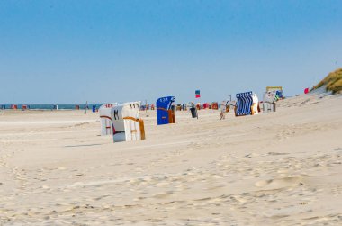 Sahilde renkli plaj sandalyeleri. Deniz ufukta görünür. Mavi, bulutsuz gökyüzü.