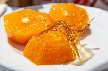 Mallorca 'da sıklıkla sunulan bir tatlı taze, sulu ve şekerli portakallardır. Dilimlenmiş portakallar beyaz bir tabakta kendi sularında yatıyor. Ön planda yarım portakallı karamelize şeker yığını var. Güneş durgun yaşamı aydınlatır.