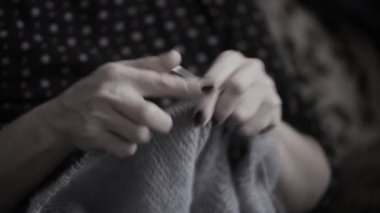 Woman hands knitting handmade wool clothes with knitting needles. Close up view.