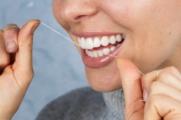 Gadis Memegang Benang Gigi Pada Latar Belakang Biru — Stok Foto
