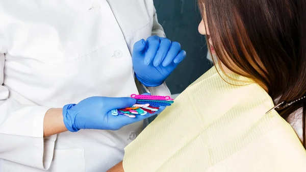 dentist orthodontist offers to choose colored gum, a girl teenager