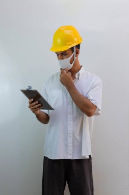 Kasklı ve salgın maskeli işçiler beyaz arka planda izole edilmiş. Siyah adam elinde çarşaf tutuyor..