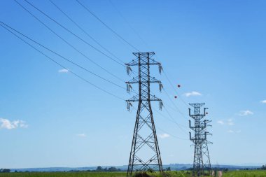 Kırsal kesimdeki yüksek voltajlı bir güç iletim kulesi gün batımında izole edilmiş ve gökyüzünde güzel sıcak bulutlar var. Yaz şehir fotoğrafçılığı. 