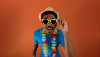 Brezilya karnavalı için kostüm giyen siyah adam turuncu arka planda izole edilmiş.