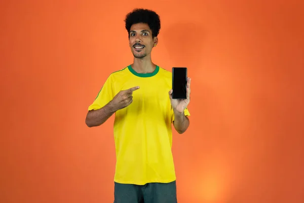 Sport Fan Celebrating Holding Mobile Isolated Orange Background — Stock Fotó