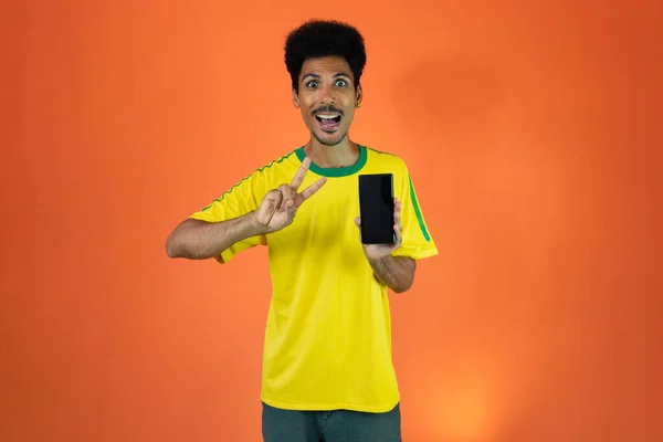 Sport Fan Celebrating Holding Mobile Isolated Orange Background — Stockfoto
