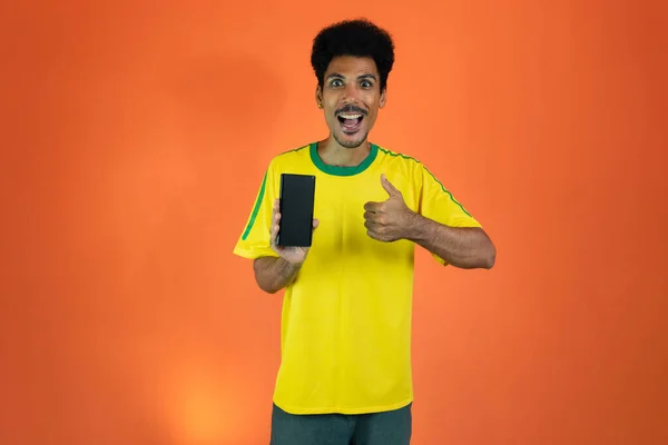 Sport Fan Celebrating Holding Mobile Isolated Orange Background —  Fotos de Stock