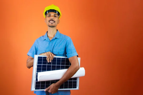 Black Man in Safety Helmet and Blue Shirt isolated. Engineer Holding Photovoltaic Solar Panel.