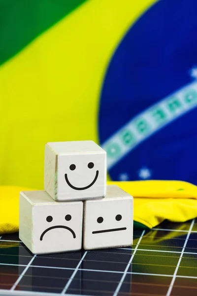 Smile Face and sad face in in wooden block cube and Brazil Flag on photovoltaic solar panel