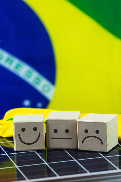 Smile Face and sad face in in wooden block cube and Brazil Flag on photovoltaic solar panel