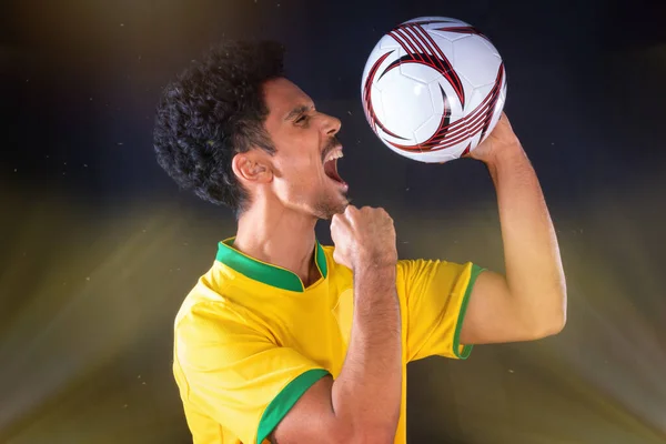 ブラジルのサッカーブラック選手ホールディングボールと祝典 黒の背景に隔離 — ストック写真