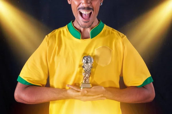 Brazilian Football Black Player Holding Winner Trophy and Celebrating, Isolated on Black Background.