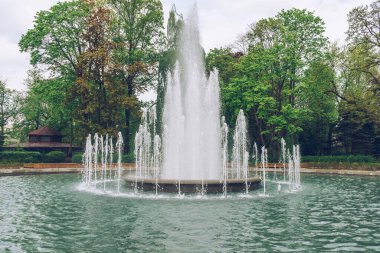 big fountain in park at spring with gloomy skies