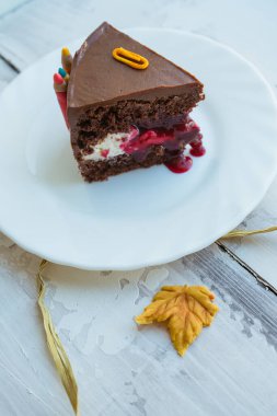Şeker tokası, kalem ve sonbahar yaprağıyla süslenmiş çikolatalı kekin dikey görüntüsü