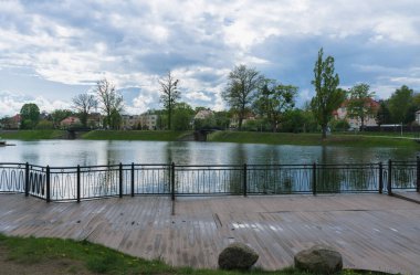 Kaliningrad, Rusya - 16 Mayıs 2021: Kasvetli bahar gününde şehir manzarası ve yürüyen insanlarla göl manzarası