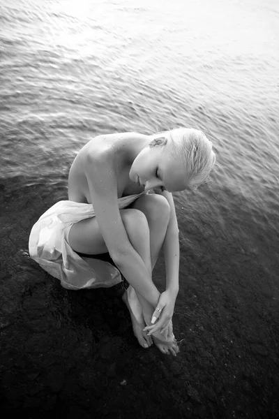 艺术裸体性感金发短发是在日落时坐在湖滨沙滩上的水 湿头发和女人的身体 隐秘的海滩假日 黑人和白人 — 图库照片
