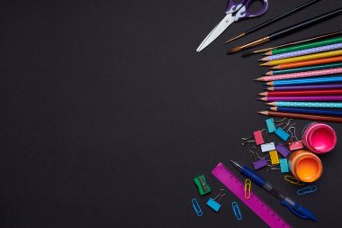 Çocuklar ders çalışmak için kırtasiye malzemesi taşıyorlar. Siyah Kağıt arkaplanındaki Kalem Cetvelini Boya