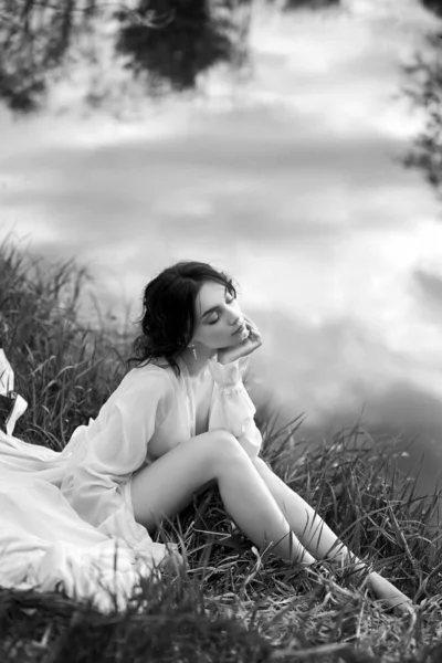 白いドレスの美しい若い女性の海岸湖の池の川に休んでいる カールした髪のプロのメイクやヘアスタイル — ストック写真