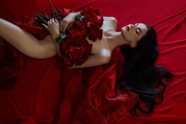 Yerde yatan kırmızı güllerle güzel, seksi esmer, çıplak vücut parçaları, erotik bir kadın portresi.