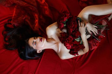 Yerde yatan kırmızı güllerle güzel, seksi esmer, çıplak vücut parçaları, erotik bir kadın portresi.