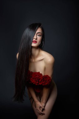 Kırmızı korseli bir buket kırmızı gül çiçeğiyle güzel esmer kadın. Uzun saç, çıplak ince vücut resmi.