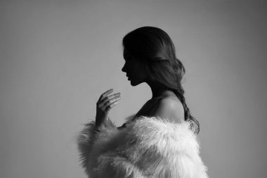 Uzun saçlı, beyaz kürklü, uzun kürklü güzel bir kadının güzel sanat portresi. Bir kadının kulaklarında güzel küpeler. Saç stili, saç stili