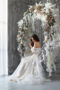 Beyaz gelinlik içinde güzel bir kadın, romantik bir görünüm, dinlenen bir kadın. Harika bir prenses. Uzun saçlı zarif bir bayan. Çatı katı tarzı iç arkaplan