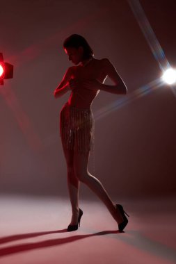 Stüdyoda poz veren güzel, çıplak, seksi, neon ışığı. Bir kadının makyaj portresi. Zayıf, mükemmel vücut, erotik poz, seksi mücevherler.