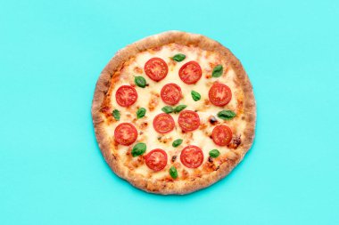 Mavi masadaki ev yapımı pizzayla en iyi manzara. Domates, mozzarella ve fesleğenden yapılmış lezzetli vejetaryen pizzası yemeye hazırım..
