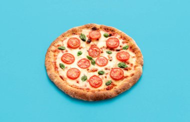 Mavi arka planda izole edilmiş vejetaryen malzemeli nefis ev yapımı pizza. Mozzarella, domates ve fesleğen yapraklı vejetaryen pizza.