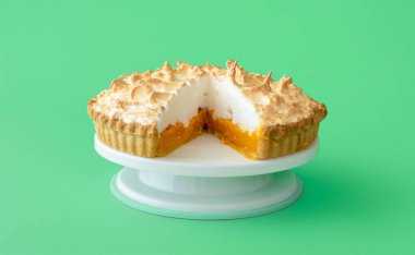 Yeşil bir masada beyaz pasta standında ev yapımı limonlu pasta. Limonlu kremalı dilimlenmiş pasta..