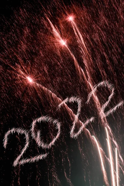 Mutlu yıllar 2022. 2022 yılında siyah arka planda havai fişeklerle parlayan yanma sayıları.