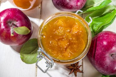 Ev yapımı altın sarısı elma reçeli, çiftlik kırmızı elmaları ve beyaz ahşap arka planda yapraklar kopyalama alanı